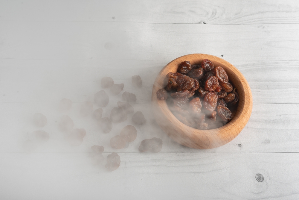 Raisins,In,A,Wooden,Saucepan,Bowl,And,On,A,Light
