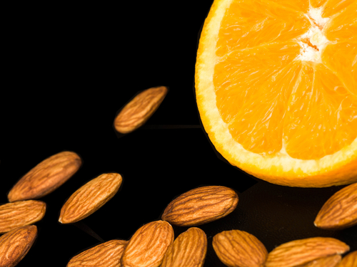 Fresh,Orange,With,Roast,Almond,Nuts,Against,A,Black,Background